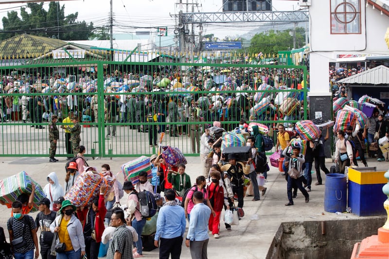 Cambodian migrant workers carry their belongings as they returned from Thailand through the Doung International Gate in Battambang province on July 28, 2025.