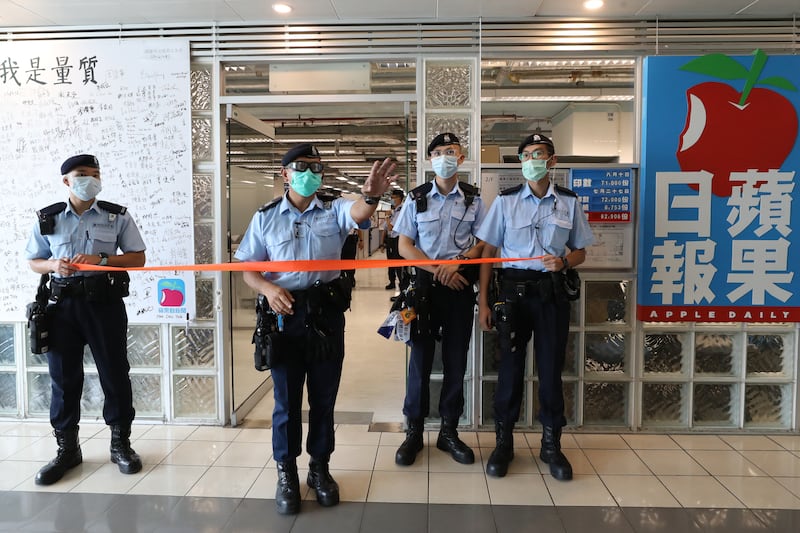 Hong Kong police officers block the entrance to Apple Daily newspaper on Aug. 10, 2020.