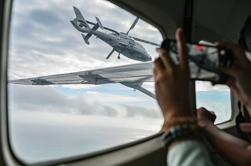 An aircraft identified by the Philippine Coast Guard as a Chinese Navy helicopter flies near a Bureau of Fisheries and Aquatic Resources plane at Scarborough Shoal in the South China Sea on Feb. 18, 2025.