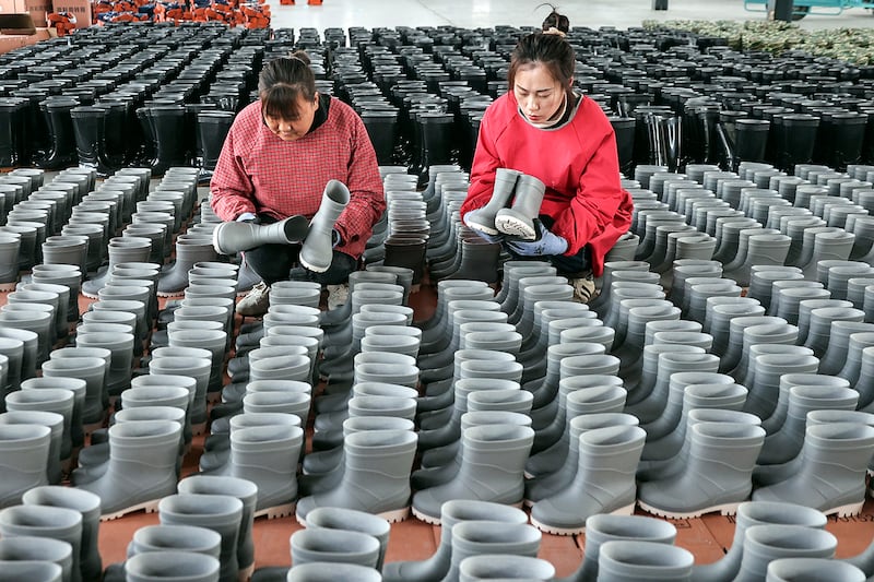 Employees check rain boots for export at a shoe factory in Lianyungang, China, March 13, 2024.