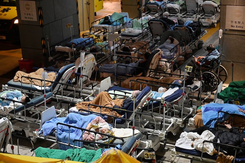 People lie in hospital beds with night-time temperatures falling outside the Caritas Medical Centre in Hong Kong on Feb. 16, 2022, as hospitals become overwhelmed with the city facing its worst COVID-19 wave to date. Credit: AFP